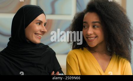 Firmenporträt zwei multirassische Frauen glücklich fröhlich lächelnd verschiedene multiethnische Geschäftsfrauen afroamerikanische Frauen und arabisch-muslimische muslime Stockfoto