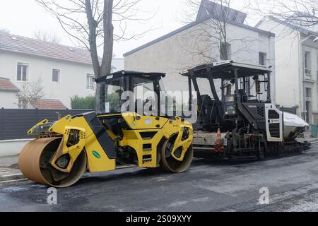 Nancy, Frankreich - Ansicht auf einer Tandemwalze Bomag BW 161 AD-5 zum Verdichten von Asphalt auf einer Straße bei Straßenarbeiten mit davor geparktem Straßenfertiger. Stockfoto