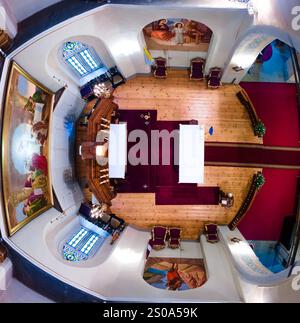 Das Bild zeigt einen Blick aus der Luft auf das Innere einer Kathedrale und zeigt einen reich verzierten Altar mit rotem Teppich, kunstvollen Stühlen und Buntglas Stockfoto