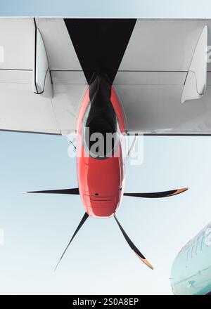 PW100-Triebwerk des Regionalflugzeugs Windrose ATR-72 - Blick unter einem Flügel: Weißer Flügel, orangefarbene Motorverkleidung, schwarzer Propeller und türkisfarbener Rumpf. Stockfoto