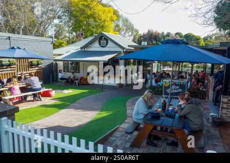 Ein lebhaftes Café im Freien in Glenbrook, in dem Familien und Freunde ihre Mahlzeiten an Picknicktischen unter Sonnenschirmen genießen, umgeben von Grün und s Stockfoto