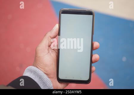 Handheld-Smartphone mit leerem Bildschirm in farbenfroher Einstellung Stockfoto