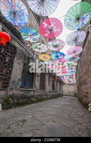 QIANDONGNAN, CHINA - 26. DEZEMBER 2024 - Ölpapierschirme, die über der Fuxing Lane hängen, hängen über der Fuxing Lane in der antiken Stadt Zhenyuan, Qiandongnan Mi Stockfoto