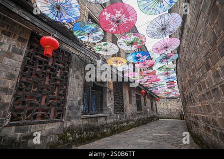QIANDONGNAN, CHINA - 26. DEZEMBER 2024 - Ölpapierschirme, die über der Fuxing Lane hängen, hängen über der Fuxing Lane in der antiken Stadt Zhenyuan, Qiandongnan Mi Stockfoto