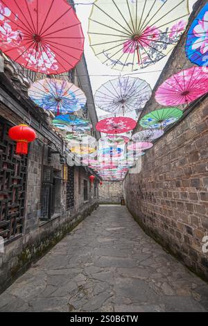QIANDONGNAN, CHINA - 26. DEZEMBER 2024 - Ölpapierschirme, die über der Fuxing Lane hängen, hängen über der Fuxing Lane in der antiken Stadt Zhenyuan, Qiandongnan Mi Stockfoto