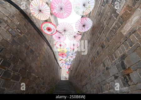 QIANDONGNAN, CHINA - 26. DEZEMBER 2024 - Ölpapierschirme, die über der Fuxing Lane hängen, hängen über der Fuxing Lane in der antiken Stadt Zhenyuan, Qiandongnan Mi Stockfoto