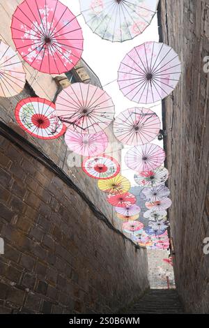 QIANDONGNAN, CHINA - 26. DEZEMBER 2024 - Ölpapierschirme, die über der Fuxing Lane hängen, hängen über der Fuxing Lane in der antiken Stadt Zhenyuan, Qiandongnan Mi Stockfoto