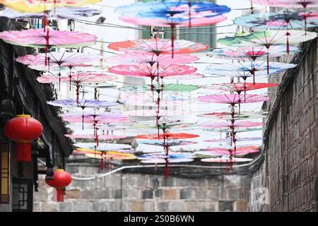 QIANDONGNAN, CHINA - 26. DEZEMBER 2024 - Ölpapierschirme, die über der Fuxing Lane hängen, hängen über der Fuxing Lane in der antiken Stadt Zhenyuan, Qiandongnan Mi Stockfoto