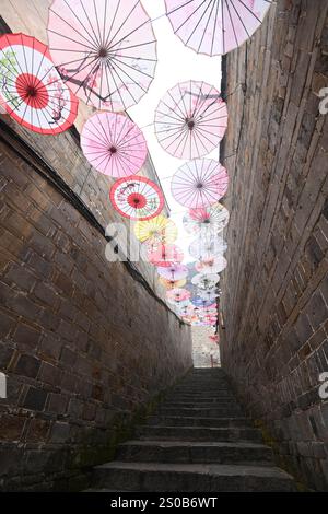 QIANDONGNAN, CHINA - 26. DEZEMBER 2024 - Ölpapierschirme, die über der Fuxing Lane hängen, hängen über der Fuxing Lane in der antiken Stadt Zhenyuan, Qiandongnan Mi Stockfoto
