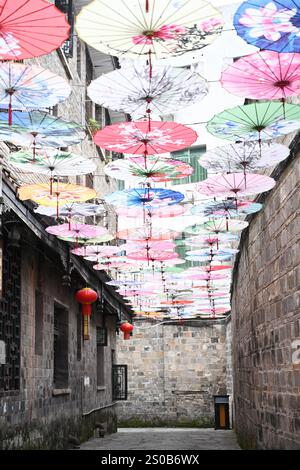 QIANDONGNAN, CHINA - 26. DEZEMBER 2024 - Ölpapierschirme, die über der Fuxing Lane hängen, hängen über der Fuxing Lane in der antiken Stadt Zhenyuan, Qiandongnan Mi Stockfoto