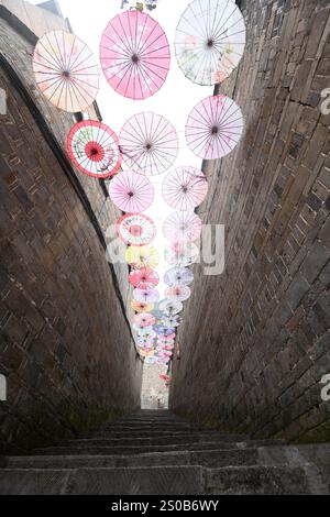 QIANDONGNAN, CHINA - 26. DEZEMBER 2024 - Ölpapierschirme, die über der Fuxing Lane hängen, hängen über der Fuxing Lane in der antiken Stadt Zhenyuan, Qiandongnan Mi Stockfoto
