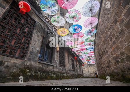 QIANDONGNAN, CHINA - 26. DEZEMBER 2024 - Ölpapierschirme, die über der Fuxing Lane hängen, hängen über der Fuxing Lane in der antiken Stadt Zhenyuan, Qiandongnan Mi Stockfoto