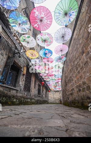 QIANDONGNAN, CHINA - 26. DEZEMBER 2024 - Ölpapierschirme, die über der Fuxing Lane hängen, hängen über der Fuxing Lane in der antiken Stadt Zhenyuan, Qiandongnan Mi Stockfoto
