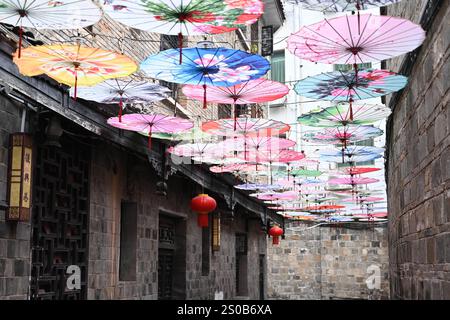 QIANDONGNAN, CHINA - 26. DEZEMBER 2024 - Ölpapierschirme, die über der Fuxing Lane hängen, hängen über der Fuxing Lane in der antiken Stadt Zhenyuan, Qiandongnan Mi Stockfoto