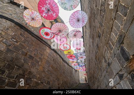 QIANDONGNAN, CHINA - 26. DEZEMBER 2024 - Ölpapierschirme, die über der Fuxing Lane hängen, hängen über der Fuxing Lane in der antiken Stadt Zhenyuan, Qiandongnan Mi Stockfoto