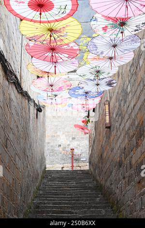 QIANDONGNAN, CHINA - 26. DEZEMBER 2024 - Ölpapierschirme, die über der Fuxing Lane hängen, hängen über der Fuxing Lane in der antiken Stadt Zhenyuan, Qiandongnan Mi Stockfoto