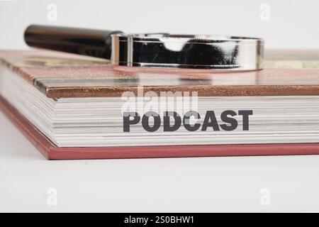 Ein Buch mit dem Titel Podcast wird auf eine Ebene Fläche gelegt, auf der eine Lupe liegt. Stockfoto