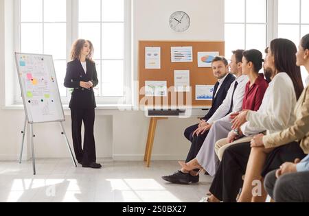 Junge Geschäftsfrau, die eine Präsentation gibt, Vorgesetzter, weibliche Coach, die den Plan auf dem Whiteboard zeigt Stockfoto