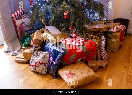 Eingewickelte Weihnachtsgeschenke unter dem Weihnachtsbaum. Eine Familie genießt ein weihnachtliches Mittagessen. Stockfoto