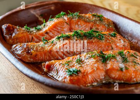 Im Ofen gebratene Lachsfilets, bestreut mit frischen grünen Kräutern und Gewürzen in einer Auflaufform, Nahaufnahme. Gesunde Ernährung Stockfoto