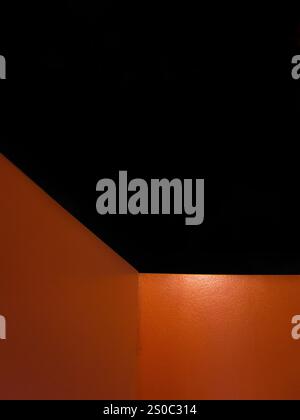 Eine schwarz-orange Wand mit einer Ecke. Die Wand ist aus Holz. Die Ecke ist abgeschnitten Stockfoto