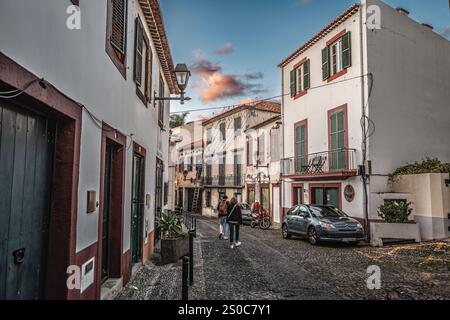 Malerische, enge Straße gesäumt von traditionellen, farbenfrohen Häusern, die ein friedliches Ambiente mit sanfter Beleuchtung bei Sonnenuntergang schaffen, die einen malerischen Charme verleiht Stockfoto