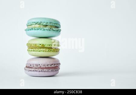 Seitenansicht Stapel von drei farbenfrohen französischen Macarons, Kuchen mit verschiedenen Aromen, Minze, Apfel, Johannisbeere Geschmack. Pyramide aus hausgemachtem Dessert, Makronen aquamaringrün, lila Farbe. Kopierbereich für Text Stockfoto