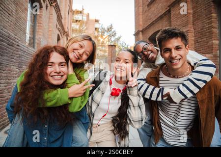 Eine Gruppe glücklicher Schüler posiert im Freien, lächelt und genießt die gemeinsame Zeit, zeigt Freundschaft, Jugend und Positivität. Teenager, die ihren Klassenkameraden einen Huckepack fahren. Hochwertige Fotos Stockfoto