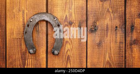 Vorderansicht einer Holztür mit einem Eisenhufeisen für viel Glück. Konzept für Glück und Glück. Ein Talisman-Aberglaube für Glück. Stockfoto