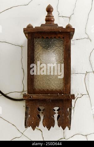 Eine hölzerne Laterne mit Ornamenten hängt an einer Wand mit aufgerissenem Putz Stockfoto