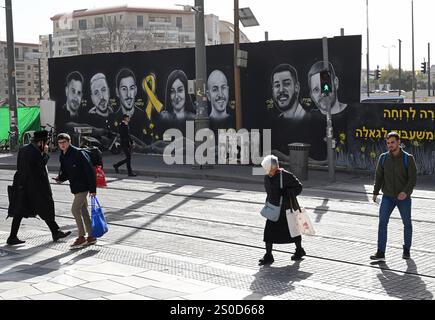 Jerusalem, Israel. Dezember 2024. Die Menschen gehen an einem Graffiti-Wandgemälde mit den Gesichtern israelischer Geiseln vorbei, die die Hamas am 448. Tag des Hamas-israelischen Krieges in Gaza festgehalten hat, am Freitag in Jerusalem, dem 27. Dezember 2024. Familien von Geiseln drohten rechtliche Schritte gegen den israelischen Ministerpräsidenten Benjamin Netanjahu und beschuldigten ihn, ihre Angehörigen im Stich zu lassen und einen Waffenstillstand und eine Freilassung von Geiseln zu blockieren. In Gaza werden noch 100 Geiseln festgehalten, und viele sind bekanntermaßen tot. Foto: Debbie Hill/ Credit: UPI/Alamy Live News Stockfoto