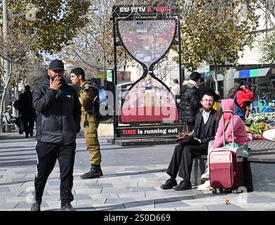 Jerusalem, Israel. Dezember 2024. Die Menschen halten eine Sanduhr für die israelischen Geiseln, die von der Hamas in Gaza am 448. Tag des Hamas-israelischen Krieges, am Freitag in Jerusalem, dem 27. Dezember 2024, festgehalten wurden. Familien von Geiseln drohten rechtliche Schritte gegen den israelischen Ministerpräsidenten Benjamin Netanjahu und beschuldigten ihn, ihre Angehörigen im Stich zu lassen und einen Waffenstillstand und eine Freilassung von Geiseln zu blockieren. In Gaza werden noch 100 Geiseln festgehalten, und viele sind bekanntermaßen tot. Foto: Debbie Hill/ Credit: UPI/Alamy Live News Stockfoto