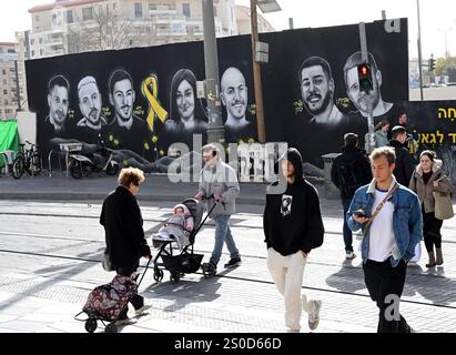 Jerusalem, Israel. Dezember 2024. Die Menschen gehen an einem Graffiti-Wandgemälde mit den Gesichtern israelischer Geiseln vorbei, die die Hamas am 448. Tag des Hamas-israelischen Krieges in Gaza festgehalten hat, am Freitag in Jerusalem, dem 27. Dezember 2024. Familien von Geiseln drohten rechtliche Schritte gegen den israelischen Ministerpräsidenten Benjamin Netanjahu und beschuldigten ihn, ihre Angehörigen im Stich zu lassen und einen Waffenstillstand und eine Freilassung von Geiseln zu blockieren. In Gaza werden noch 100 Geiseln festgehalten, und viele sind bekanntermaßen tot. Foto: Debbie Hill/ Credit: UPI/Alamy Live News Stockfoto