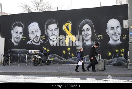 Jerusalem, Israel. Dezember 2024. Ultra-orthodoxe Jungen laufen an einem Graffiti-Wandgemälde mit den Gesichtern israelischer Geiseln vorbei, die die Hamas am 448. Tag des Hamas-israelischen Krieges in Gaza festgehalten hat, am Freitag in Jerusalem, dem 27. Dezember 2024. Familien von Geiseln drohten rechtliche Schritte gegen den israelischen Ministerpräsidenten Benjamin Netanjahu und beschuldigten ihn, ihre Angehörigen im Stich zu lassen und einen Waffenstillstand und eine Freilassung von Geiseln zu blockieren. In Gaza werden noch 100 Geiseln festgehalten, und viele sind bekanntermaßen tot. Foto: Debbie Hill/ Credit: UPI/Alamy Live News Stockfoto