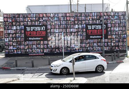 Jerusalem, Israel. Dezember 2024. Ein Auto fährt an einer großen Werbetafel mit der Aufschrift "#BRINGTHEMHOMENOW" vorbei, auf der die Gesichter israelischer Geiseln dargestellt sind, die die Hamas am 448. Tag des Hamas-israelischen Krieges in Gaza festgehalten hat, am Freitag, den 27. Dezember 2024, in Jerusalem. Familien von Geiseln drohten rechtliche Schritte gegen den israelischen Ministerpräsidenten Benjamin Netanjahu und beschuldigten ihn, ihre Angehörigen im Stich zu lassen und einen Waffenstillstand und eine Freilassung von Geiseln zu blockieren. In Gaza werden noch 100 Geiseln festgehalten, und viele sind bekanntermaßen tot. Foto: Debbie Hill/ Credit: UPI/Alamy Live News Stockfoto