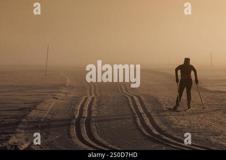 Oberstdorf, Deutschland. Dezember 2024. Ein Skilangläufer gleitet im Nebel der Abendsonne über eine Strecke. Vermerk: Daniel Karmann/dpa/Alamy Live News Stockfoto