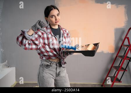 Überraschte, schockierte Malerin mit Roller. Renovierung, Renovierung, Reparaturkonzept für Wohnungen. Stockfoto