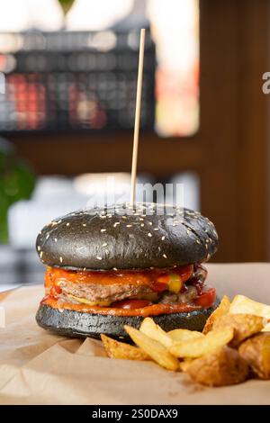 Saftiger, zarter Hamburger mit Schnitzel und Bratkartoffeln liegt auf dem Tisch im Café. Ungesundes Essen.. ?Opy Space Stockfoto