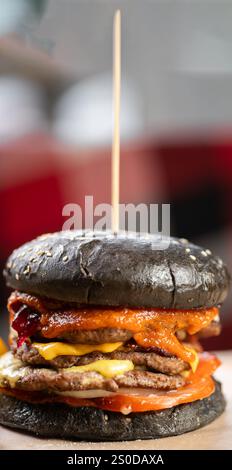 Nahaufnahme von doppeltem Black Brötchen Burger mit saftigem Rindfleischpatty. Ungesunde Nahrung. Bestellen Sie im Restaurant. ?Opy Space Stockfoto