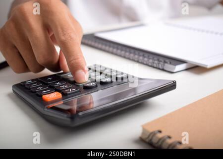 Machen Sie Geschäftsleute mit Taschenrechner hautnah, um die Finanzierung zu berechnen und Notizen zu schreiben, Buchhaltung am Schreibtisch zu erstellen und Budgetverwaltung zu verwalten. Finanzen, Budgets Stockfoto