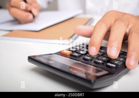 Machen Sie Geschäftsleute mit Taschenrechner hautnah, um die Finanzierung zu berechnen und Notizen zu schreiben, Buchhaltung am Schreibtisch zu erstellen und Budgetverwaltung zu verwalten. Finanzen, Budgets Stockfoto