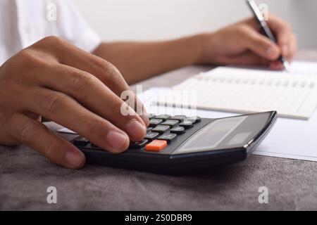 Machen Sie Geschäftsleute mit Taschenrechner hautnah, um die Finanzierung zu berechnen und Notizen zu schreiben, Buchhaltung am Schreibtisch zu erstellen und Budgetverwaltung zu verwalten. Finanzen, Budgets Stockfoto