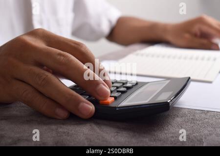 Machen Sie Geschäftsleute mit Taschenrechner hautnah, um die Finanzierung zu berechnen und Notizen zu schreiben, Buchhaltung am Schreibtisch zu erstellen und Budgetverwaltung zu verwalten. Finanzen, Budgets Stockfoto