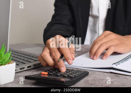 Machen Sie Geschäftsleute mit Taschenrechner hautnah, um die Finanzierung zu berechnen und Notizen zu schreiben, Buchhaltung am Schreibtisch zu erstellen und Budgetverwaltung zu verwalten. Finanzen, Budgets Stockfoto