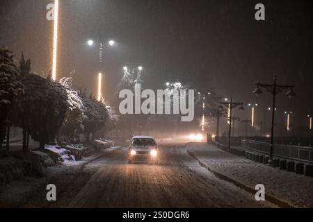 Ein Fahrzeug fährt während des Schneefalls auf der schneebedeckten Straße in Srinagar, der Sommerhauptstadt von Jammu und Kaschmir. Stockfoto