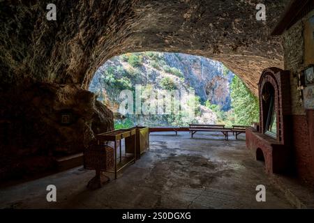 Blick aus dem Inneren des Höhlentempels von Panagia Lagadiotissa mit seiner natürlichen Felsstruktur und der umliegenden ruhigen Landschaft. Stockfoto