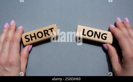 Symbol kurz vs lang. Konzeptwort kurz vs lang auf Holzblöcken. Geschäftsmann Hand. Schöner grauer Hintergrund. Business und kurz- vs Langkonzept. Co Stockfoto