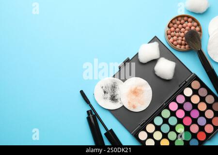 Flache Lay-Komposition mit Wattepads und Make-up-Produkten auf hellblauem Hintergrund, Platz für Text Stockfoto