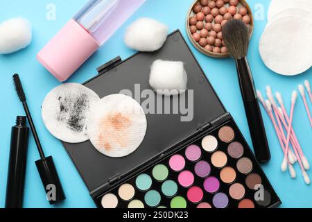 Flache Lay-Komposition mit Wattepads und Make-up-Produkten auf hellblauem Hintergrund Stockfoto