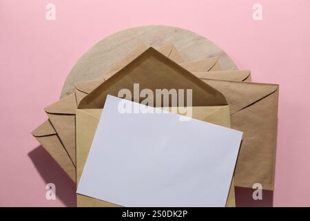 Kraftpapier-Umschläge und Briefumschläge auf rosafarbenem Hintergrund, Draufsicht. Modell für Design Stockfoto